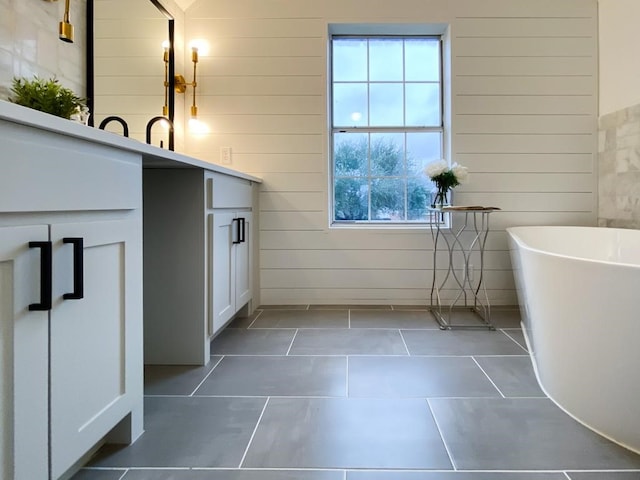 bathroom featuring vanity, tile patterned floors, a freestanding tub, and wood walls