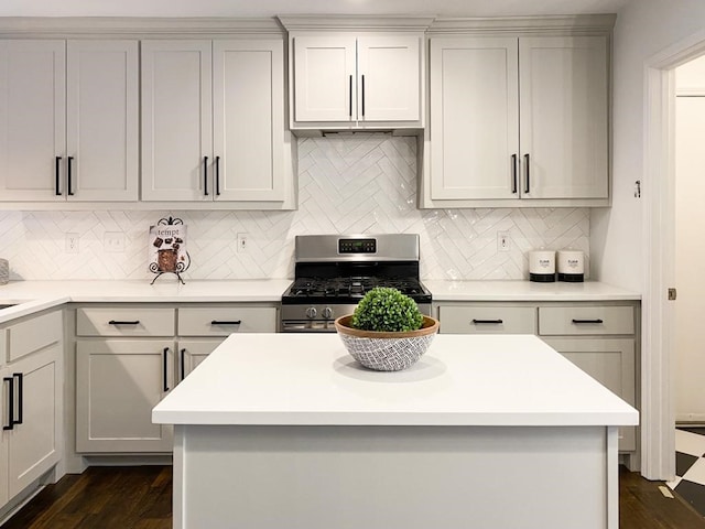 kitchen with tasteful backsplash, stainless steel range with gas stovetop, light countertops, gray cabinets, and dark wood-style flooring