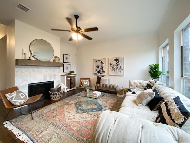 living room featuring visible vents, wood finished floors, ornamental molding, and a fireplace