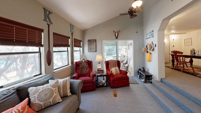 carpeted living area with arched walkways, high vaulted ceiling, and a ceiling fan