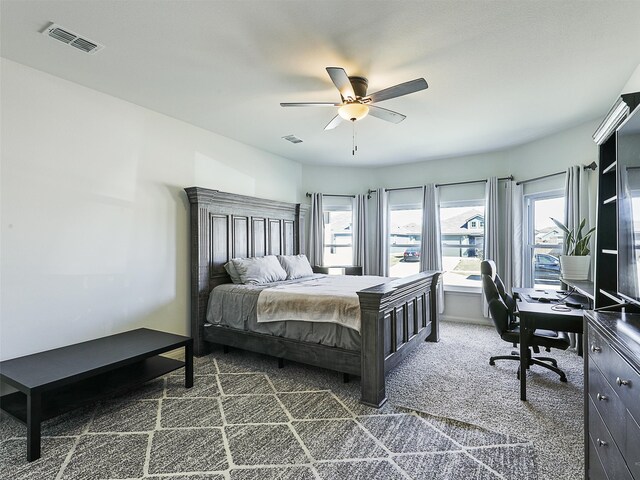 bedroom with multiple windows, a ceiling fan, visible vents, and dark carpet