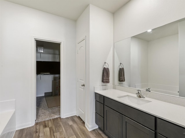 bathroom with vanity, a garden tub, wood finished floors, and baseboards