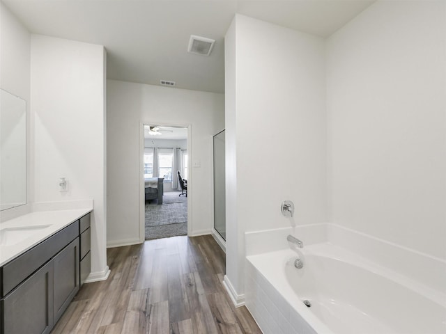 bathroom with visible vents, connected bathroom, vanity, and a garden tub