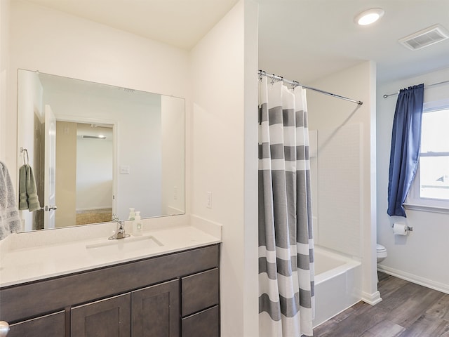 bathroom featuring visible vents, toilet, wood finished floors, shower / bath combination with curtain, and vanity