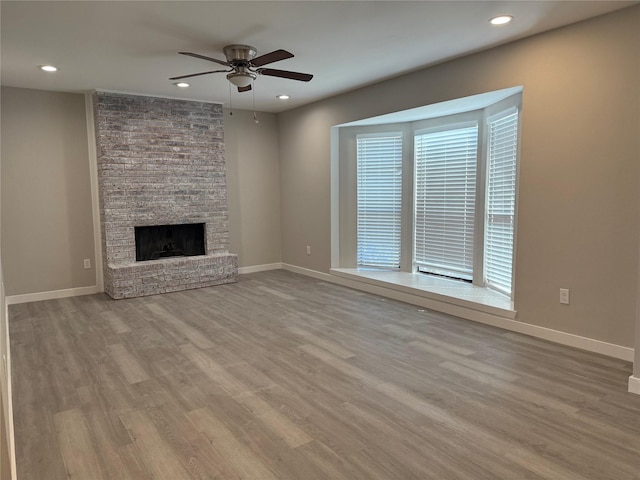 unfurnished living room featuring baseboards, a large fireplace, and wood finished floors