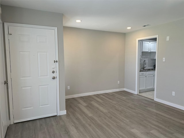 spare room featuring a sink, recessed lighting, baseboards, and wood finished floors