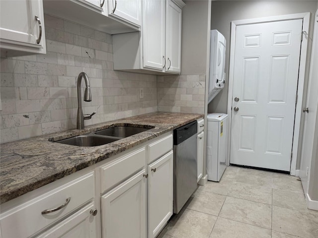 kitchen featuring a sink, stacked washer and clothes dryer, dark stone counters, and stainless steel dishwasher