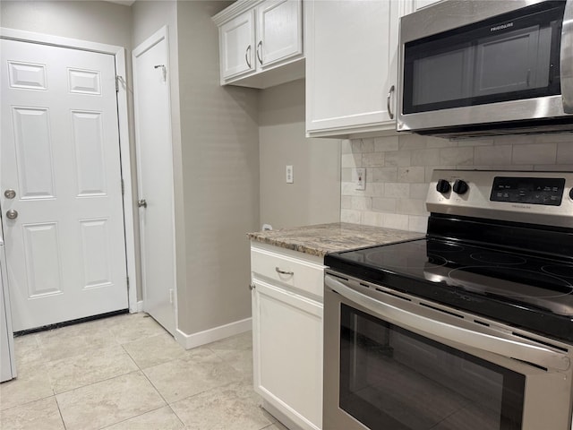 kitchen featuring light stone countertops, light tile patterned flooring, appliances with stainless steel finishes, white cabinetry, and backsplash