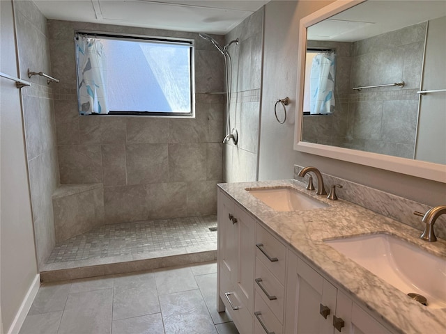 bathroom featuring double vanity, tiled shower, and a sink