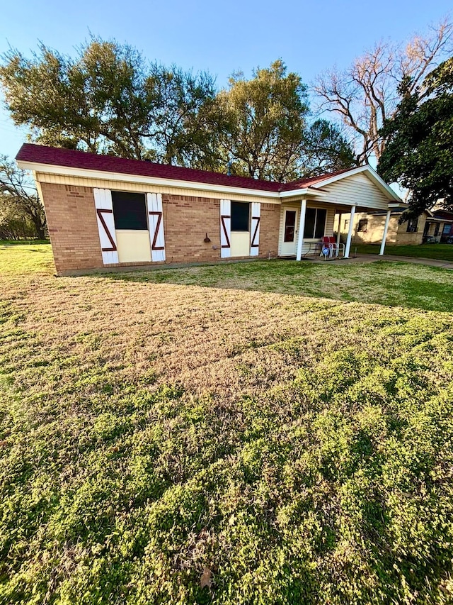 back of property featuring a yard and brick siding