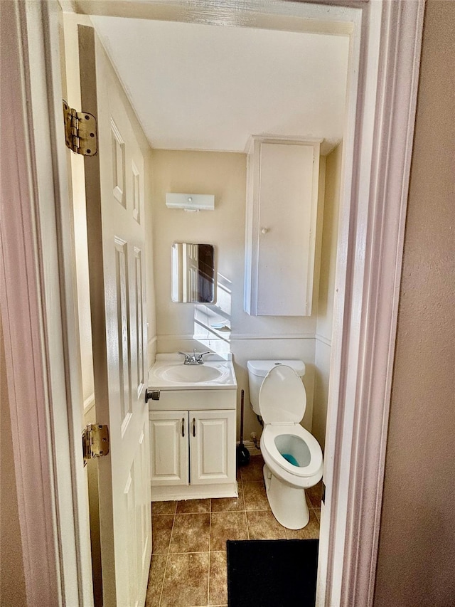 half bathroom with vanity, tile patterned floors, and toilet