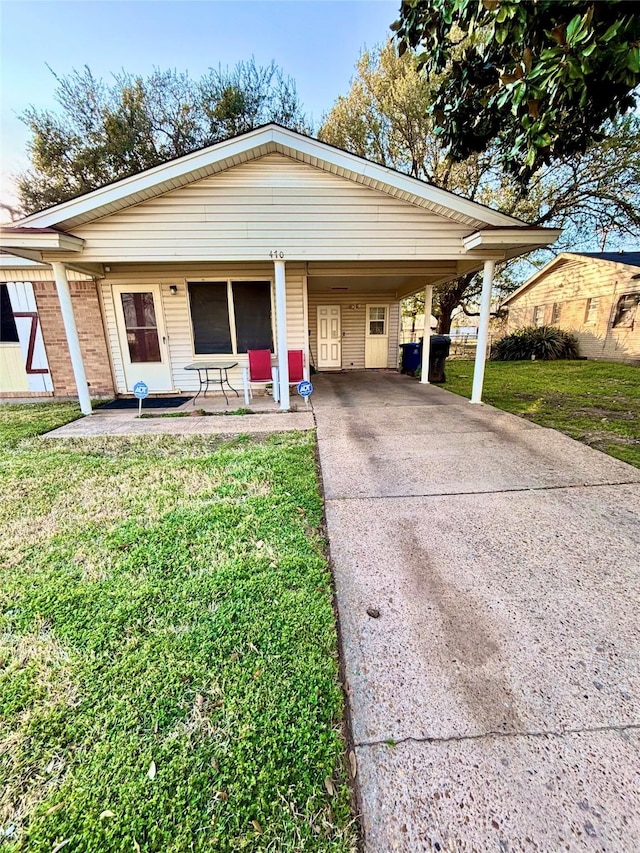 view of front facade with a carport, a front yard, and driveway