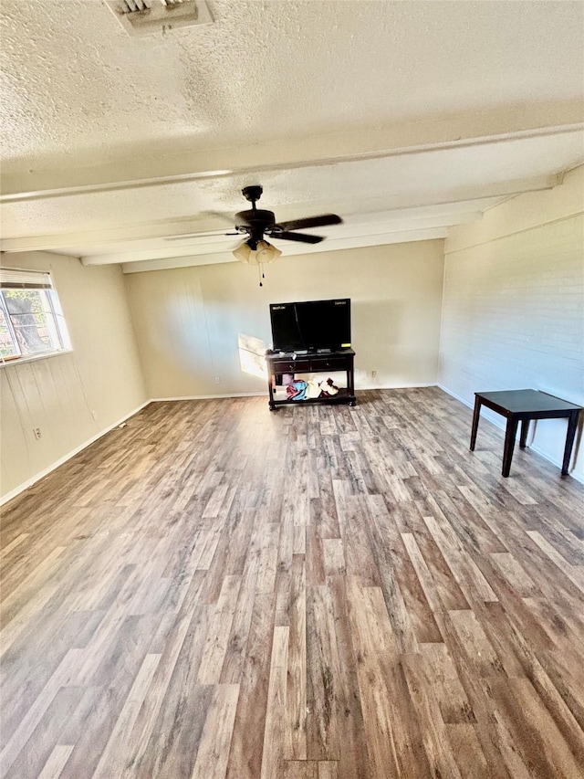 unfurnished living room featuring visible vents, beam ceiling, a ceiling fan, a textured ceiling, and wood finished floors