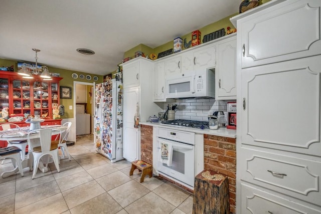 kitchen with white appliances, light tile patterned floors, washer / dryer, light countertops, and white cabinets