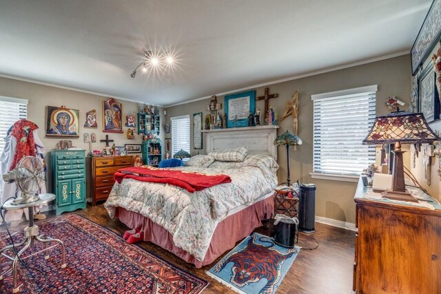 bedroom with wood finished floors, baseboards, and ornamental molding