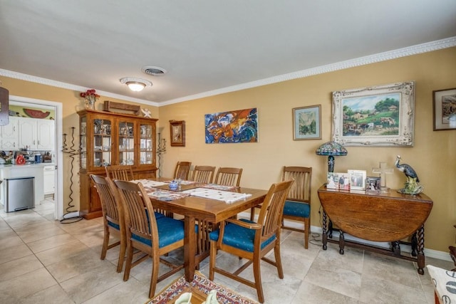 dining space with light tile patterned floors, visible vents, crown molding, and baseboards