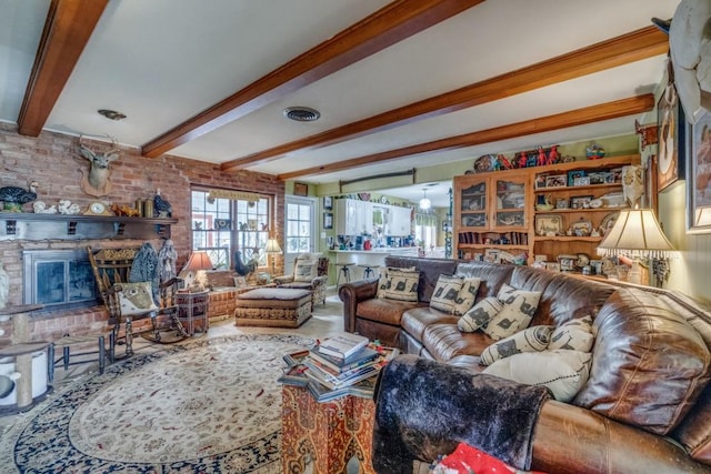 living area with visible vents, beam ceiling, and a brick fireplace