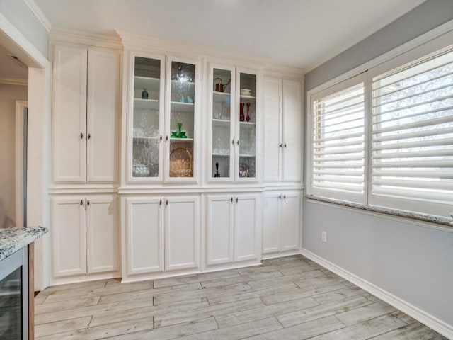 unfurnished dining area with light wood finished floors, crown molding, and baseboards