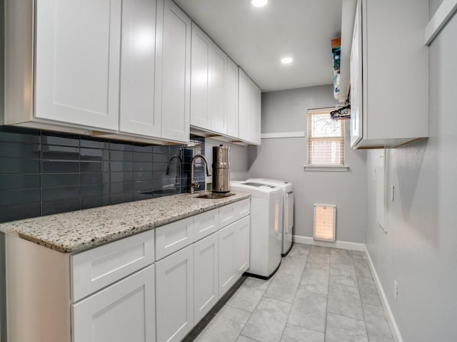 clothes washing area with baseboards, recessed lighting, separate washer and dryer, cabinet space, and a sink