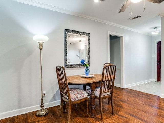 dining room with visible vents, ornamental molding, a ceiling fan, wood finished floors, and baseboards