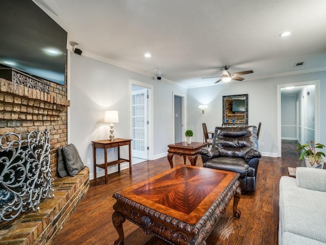 living area featuring crown molding, a brick fireplace, wood finished floors, and baseboards