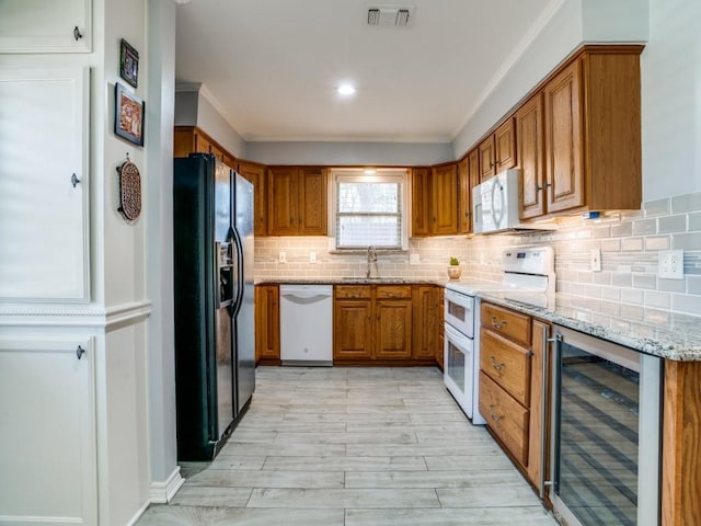 kitchen with white appliances, light stone counters, visible vents, wine cooler, and brown cabinets