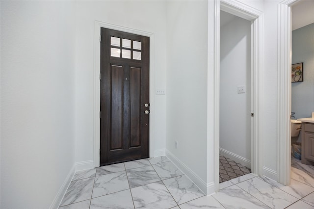 foyer entrance with marble finish floor and baseboards