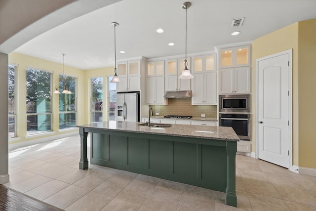 kitchen with a sink, decorative backsplash, stainless steel appliances, white cabinets, and under cabinet range hood