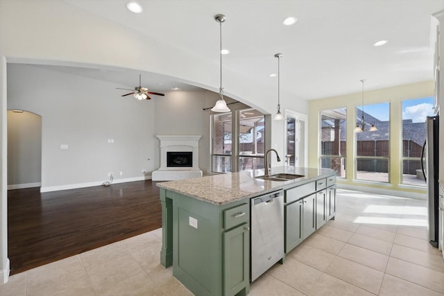 kitchen with green cabinets, light tile patterned floors, arched walkways, stainless steel appliances, and a sink