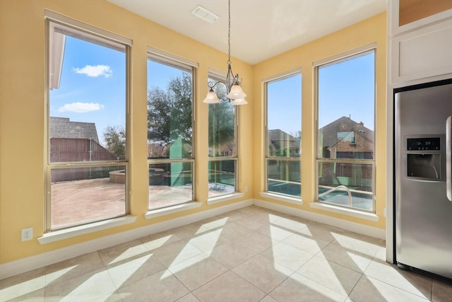 unfurnished sunroom with a wealth of natural light, visible vents, and an inviting chandelier