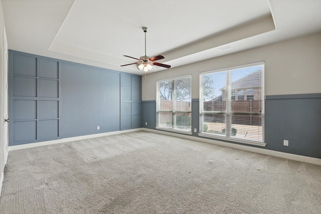 spare room featuring visible vents, baseboards, carpet flooring, a raised ceiling, and ceiling fan