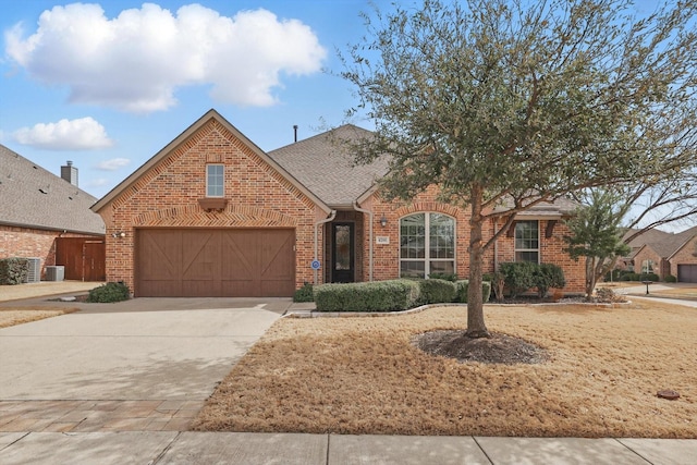 traditional-style house featuring brick siding, concrete driveway, a garage, and a shingled roof