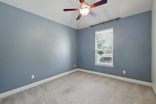 carpeted spare room featuring a ceiling fan, baseboards, and vaulted ceiling