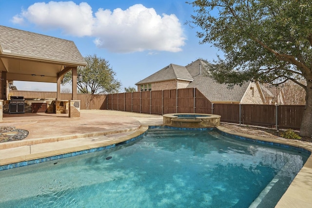 view of pool with a patio area, a fenced backyard, a pool with connected hot tub, and an outdoor kitchen