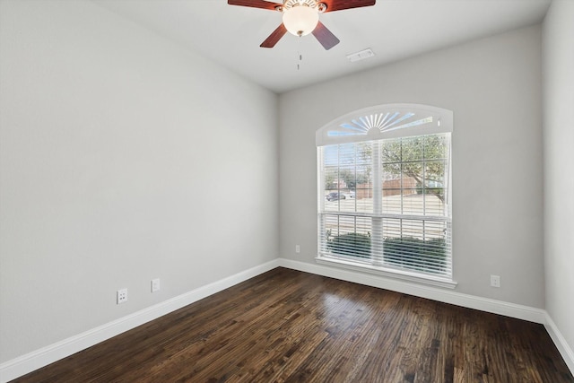 unfurnished room featuring visible vents, baseboards, dark wood-style floors, and a ceiling fan