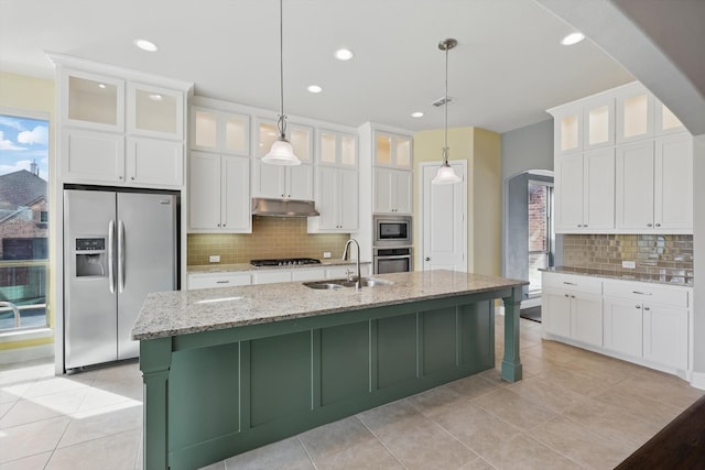 kitchen featuring a sink, under cabinet range hood, arched walkways, appliances with stainless steel finishes, and white cabinets