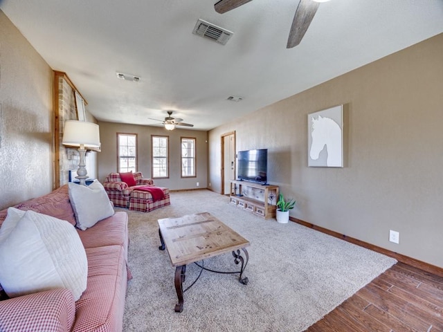 living room featuring visible vents, baseboards, a ceiling fan, and wood finished floors