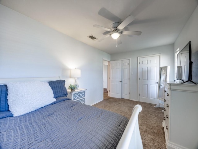 carpeted bedroom with ceiling fan, baseboards, visible vents, and multiple closets