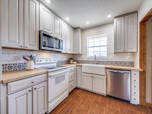 kitchen with recessed lighting, a sink, stainless steel appliances, dark wood-type flooring, and backsplash