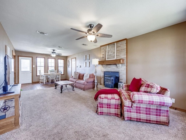 living room featuring visible vents, carpet floors, a textured ceiling, and a ceiling fan