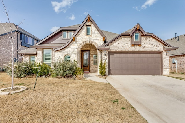 french provincial home featuring brick siding, an attached garage, roof with shingles, and driveway