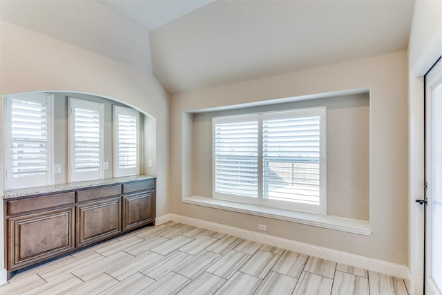 spare room with baseboards, plenty of natural light, and lofted ceiling