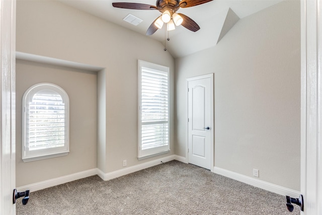 empty room with vaulted ceiling, a healthy amount of sunlight, visible vents, and carpet floors