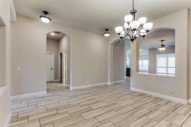 unfurnished room with baseboards, arched walkways, and ceiling fan with notable chandelier