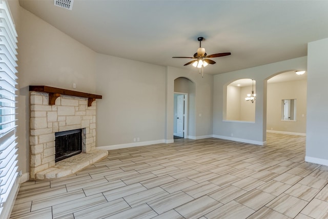 unfurnished living room featuring visible vents, baseboards, a fireplace, arched walkways, and a ceiling fan