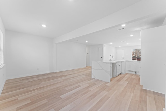 unfurnished living room featuring visible vents, recessed lighting, light wood-style floors, and a sink