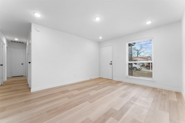 spare room featuring visible vents, baseboards, and light wood-style floors