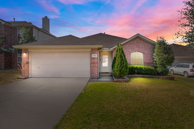 ranch-style home with brick siding, roof with shingles, a lawn, a garage, and driveway