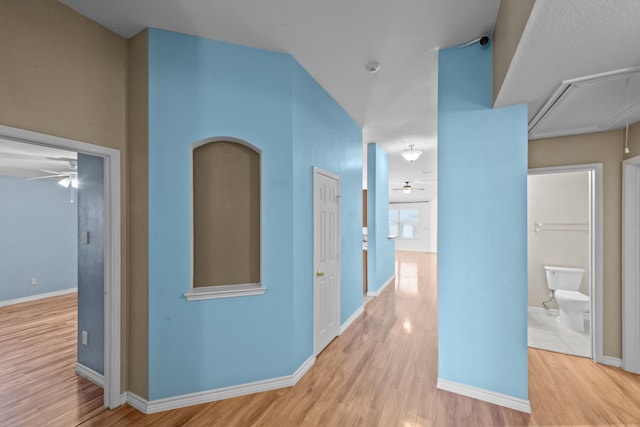 corridor with attic access, baseboards, and wood finished floors