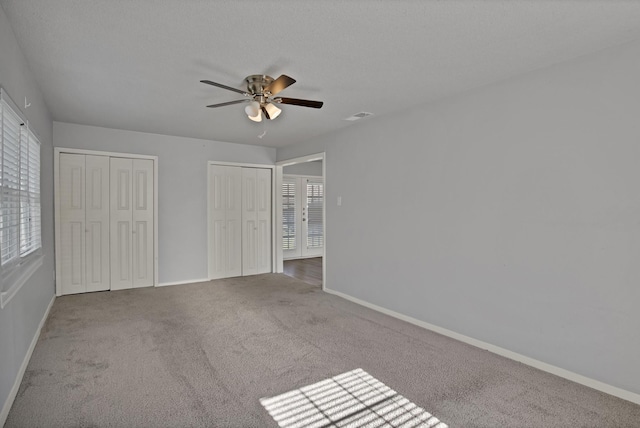 unfurnished bedroom featuring visible vents, carpet floors, two closets, and baseboards